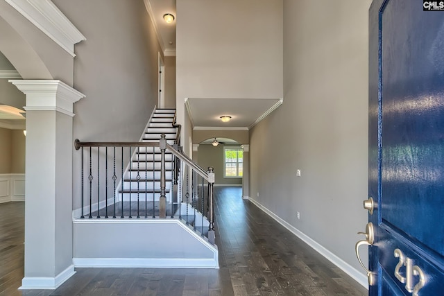 foyer featuring crown molding, dark hardwood / wood-style flooring, and ornate columns