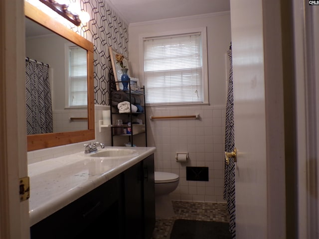 bathroom with tile patterned flooring, crown molding, toilet, vanity, and tile walls