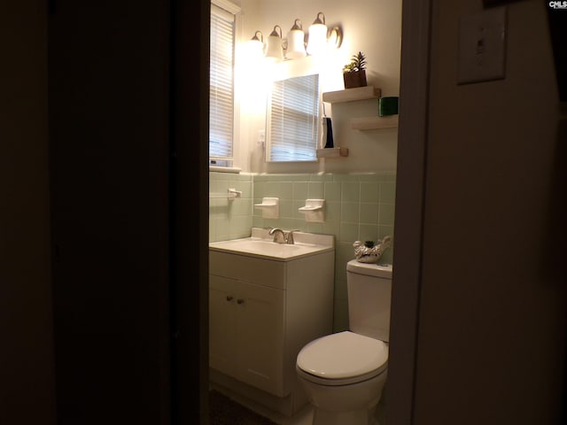 bathroom with vanity, toilet, and tile walls