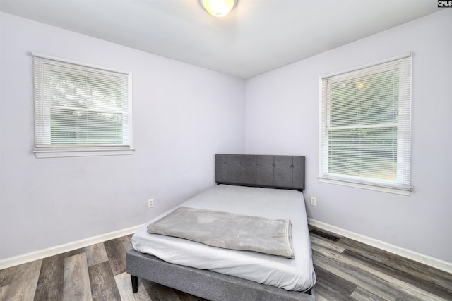 bedroom featuring dark hardwood / wood-style flooring and multiple windows