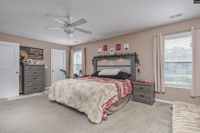 carpeted bedroom with multiple windows and ceiling fan