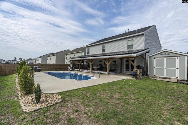 back of house featuring a storage shed, a fenced in pool, a lawn, and a patio area