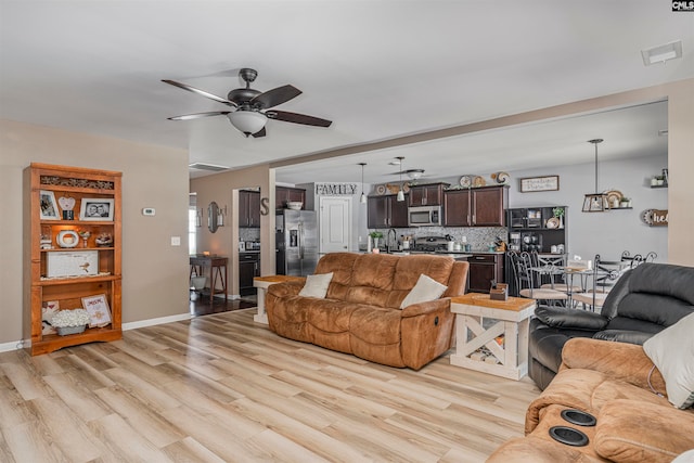 living room featuring sink, light hardwood / wood-style flooring, and ceiling fan