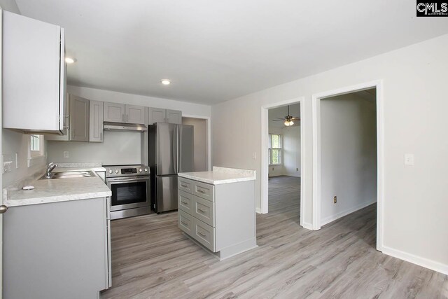 kitchen with stove, light hardwood / wood-style flooring, stainless steel fridge, gray cabinetry, and a center island