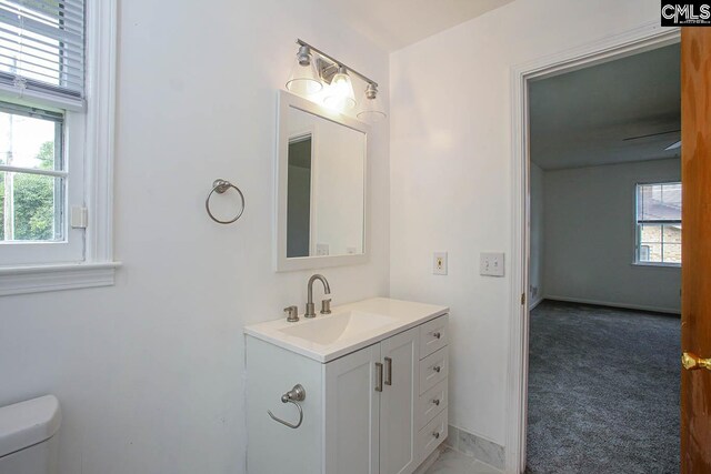 bathroom with a healthy amount of sunlight, vanity, and toilet