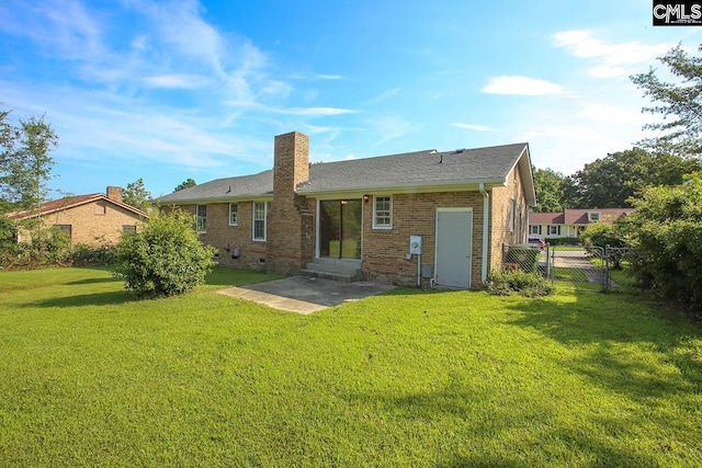 back of property with entry steps, brick siding, a lawn, a chimney, and a patio area