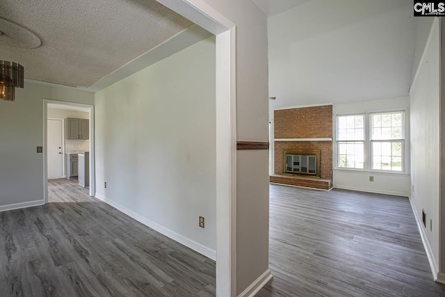 interior space featuring hardwood / wood-style flooring, a brick fireplace, brick wall, and a textured ceiling