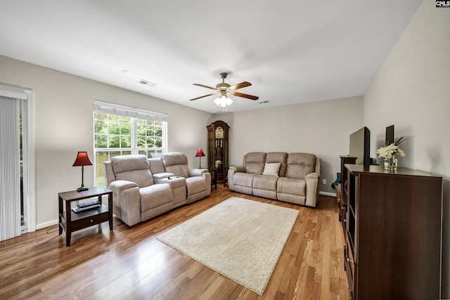 living room featuring baseboards, ceiling fan, visible vents, and light wood-style floors