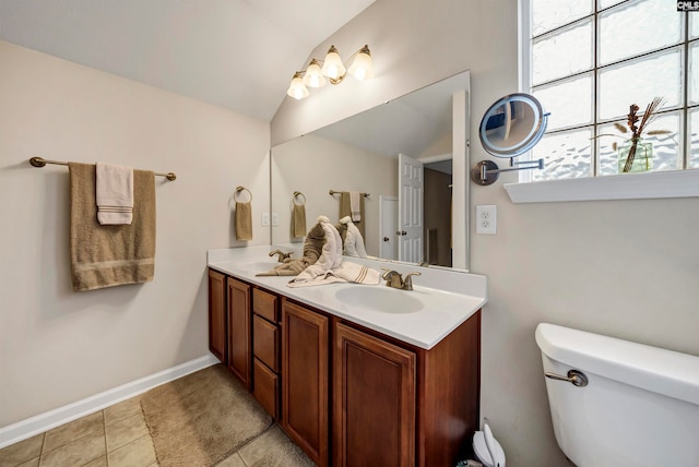 bathroom featuring double vanity, tile patterned floors, toilet, and vaulted ceiling