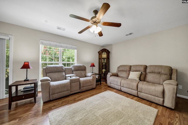 living room featuring a ceiling fan, baseboards, visible vents, and wood finished floors