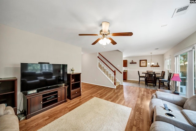 living room featuring light hardwood / wood-style flooring and ceiling fan with notable chandelier