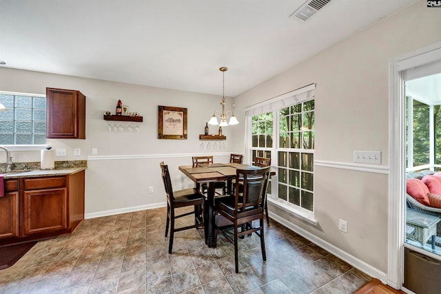 tiled dining area featuring sink, a notable chandelier, and a healthy amount of sunlight