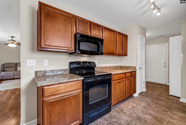 kitchen with rail lighting, light stone counters, ceiling fan, tile patterned floors, and black appliances