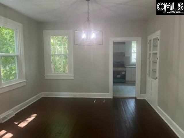 unfurnished dining area featuring plenty of natural light and dark hardwood / wood-style flooring