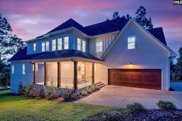 view of front facade featuring covered porch, a garage, concrete driveway, a front lawn, and board and batten siding