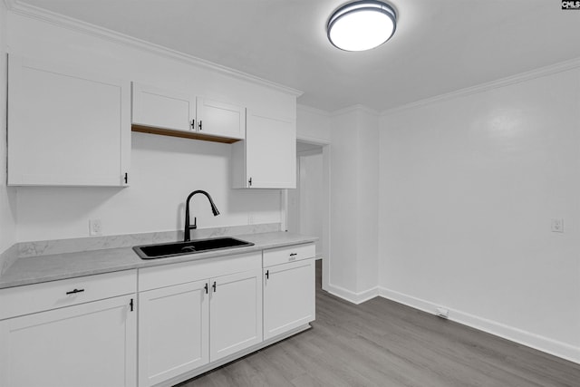 kitchen featuring light hardwood / wood-style floors, sink, white cabinetry, and crown molding