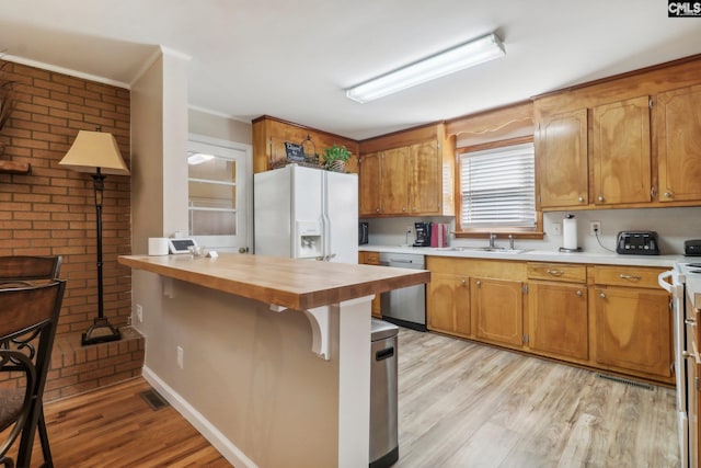 kitchen with wood counters, stainless steel dishwasher, light wood-style floors, white fridge with ice dispenser, and a sink