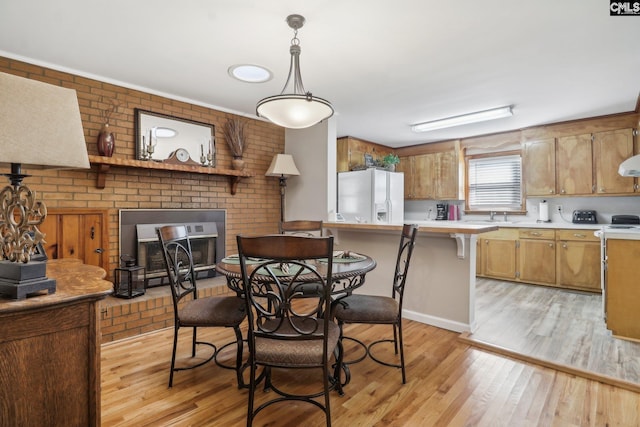 dining area featuring light wood-type flooring and a brick fireplace