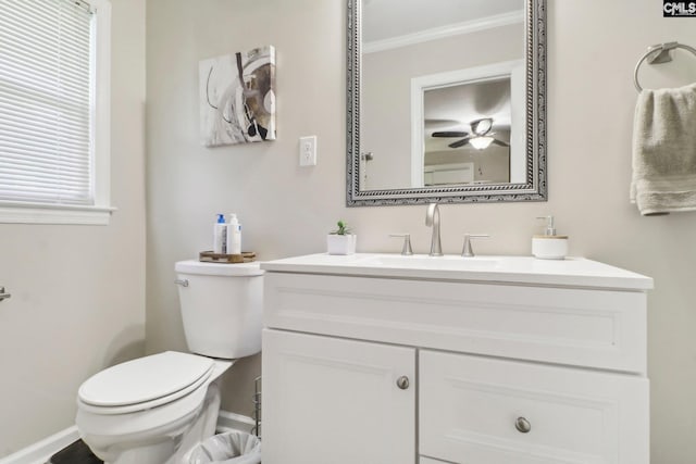 half bathroom featuring baseboards, a ceiling fan, toilet, ornamental molding, and vanity