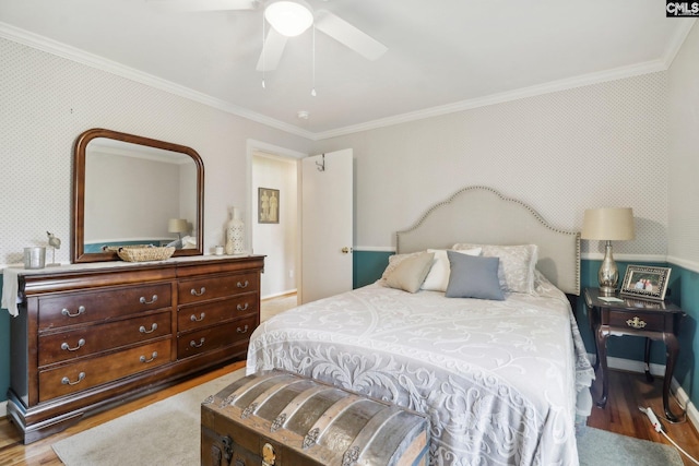 bedroom featuring ornamental molding, wood finished floors, baseboards, and wallpapered walls