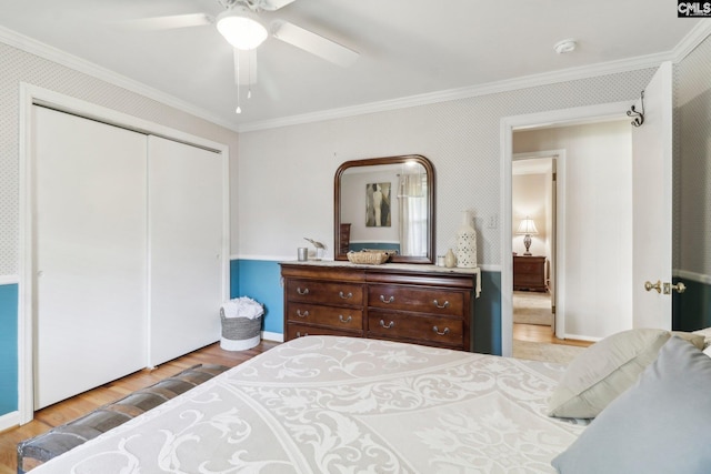 bedroom with wallpapered walls, light wood-style flooring, ornamental molding, and a closet