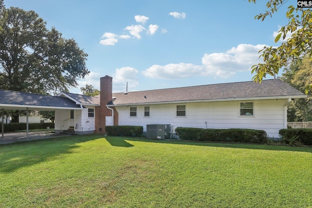 back of house featuring a lawn, a chimney, and central air condition unit