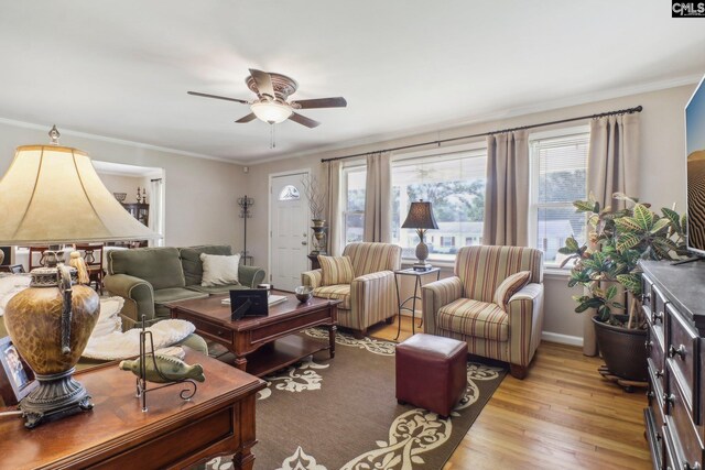 living area featuring light wood-style flooring, ornamental molding, ceiling fan, and baseboards