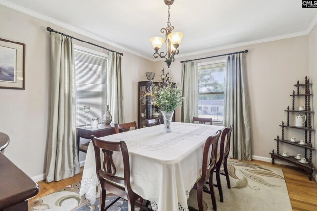 dining space featuring ornamental molding, light wood finished floors, baseboards, and an inviting chandelier