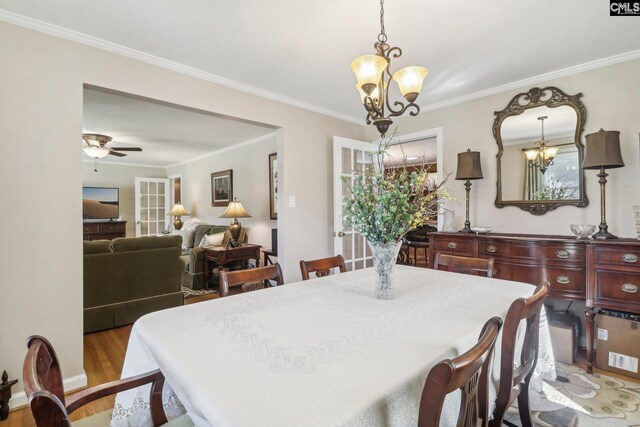 dining space featuring light wood-style flooring, crown molding, and ceiling fan with notable chandelier