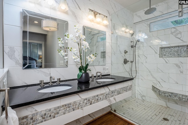 bathroom with dual bowl vanity, tile walls, tiled shower, and decorative backsplash