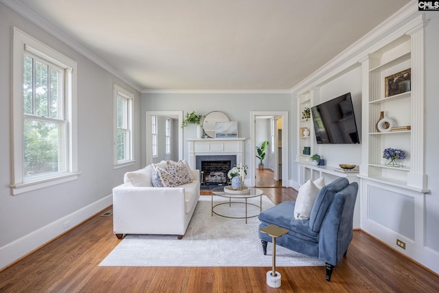 living room featuring hardwood / wood-style floors, built in shelves, and ornamental molding