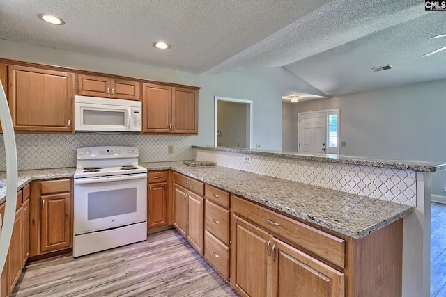 kitchen with a textured ceiling, white appliances, backsplash, light hardwood / wood-style floors, and kitchen peninsula