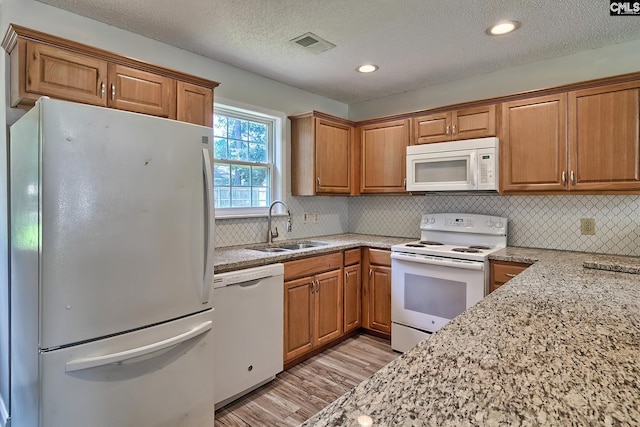 kitchen featuring sink, light hardwood / wood-style flooring, a textured ceiling, and white appliances