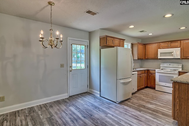 kitchen featuring a textured ceiling, light wood-type flooring, white appliances, and a notable chandelier