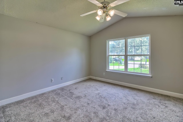 empty room featuring ceiling fan, vaulted ceiling, a textured ceiling, and carpet flooring