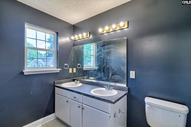 bathroom featuring double vanity, a textured ceiling, and toilet