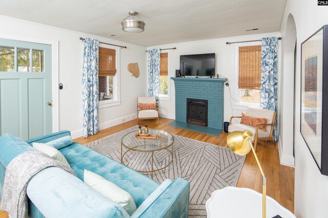 living room with a brick fireplace and light hardwood / wood-style floors