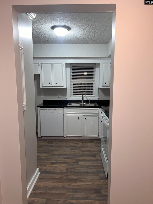 kitchen featuring white appliances, dark wood finished floors, a sink, white cabinetry, and dark countertops