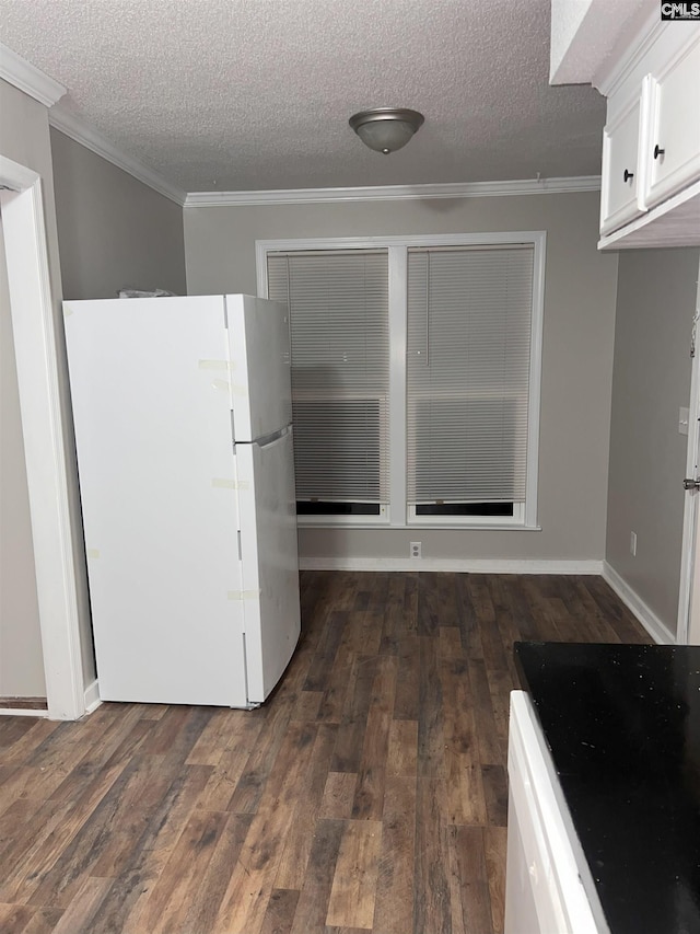 kitchen featuring ornamental molding, a textured ceiling, dark wood-style floors, white cabinetry, and freestanding refrigerator