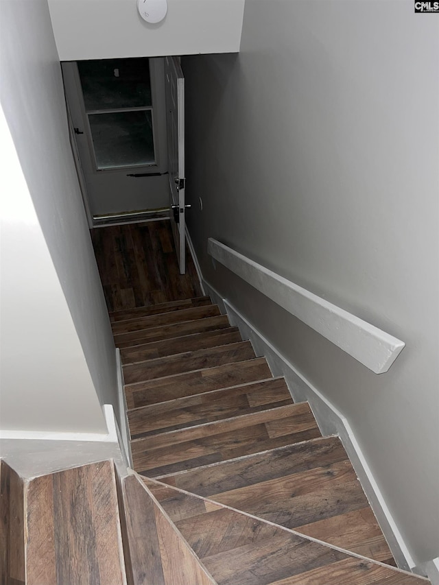 stairway with wood finished floors and baseboards