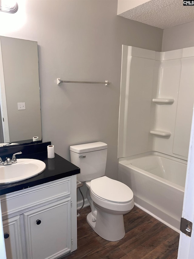 full bath featuring vanity, toilet, wood finished floors, and a textured ceiling