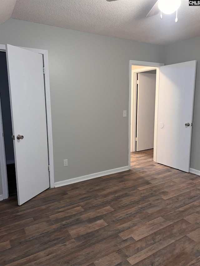 empty room featuring dark wood finished floors, baseboards, and a textured ceiling