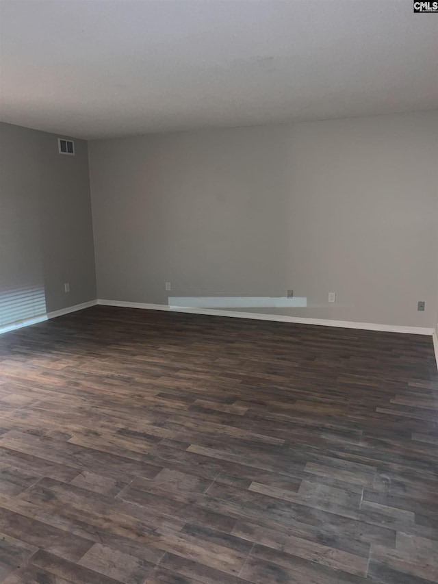 unfurnished room featuring baseboards, visible vents, and dark wood-style flooring