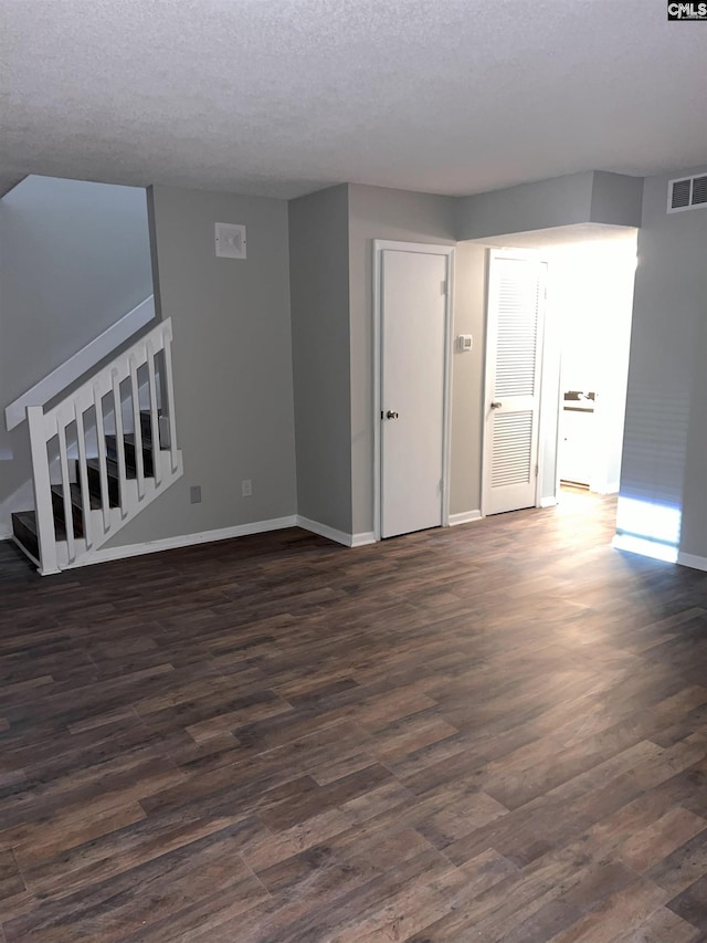 unfurnished living room featuring dark wood-style floors, visible vents, stairway, and baseboards