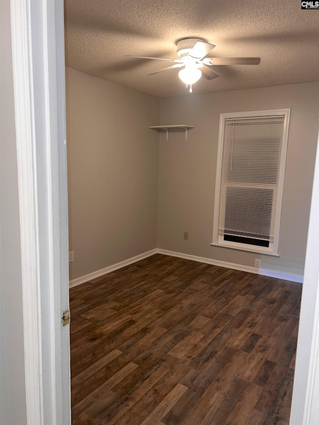 spare room featuring dark wood-style floors, a textured ceiling, baseboards, and ceiling fan