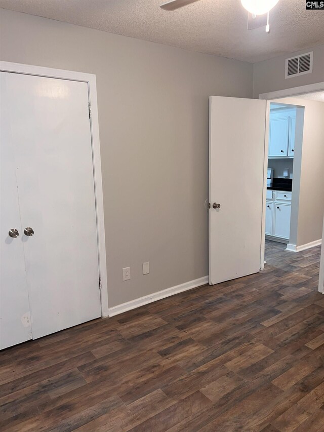 unfurnished room featuring baseboards, visible vents, dark wood-style flooring, ceiling fan, and a textured ceiling