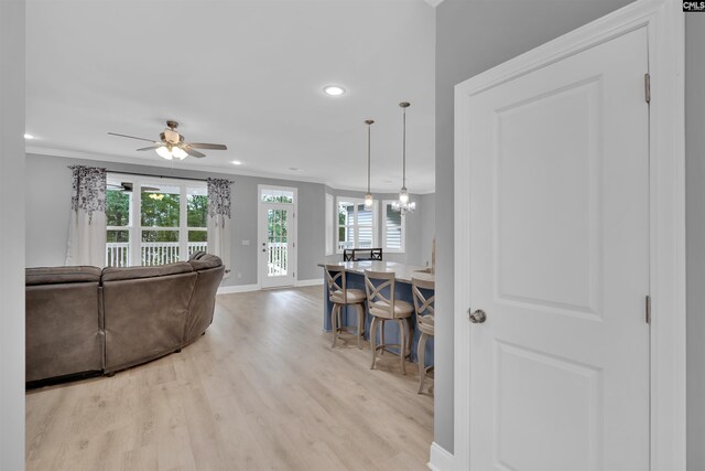 living room featuring ceiling fan, crown molding, and light hardwood / wood-style floors