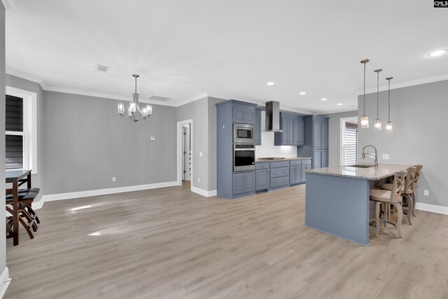 kitchen with appliances with stainless steel finishes, hanging light fixtures, wall chimney exhaust hood, a kitchen breakfast bar, and light wood-type flooring