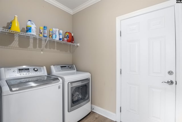 laundry room with wood-type flooring, washer and clothes dryer, and crown molding