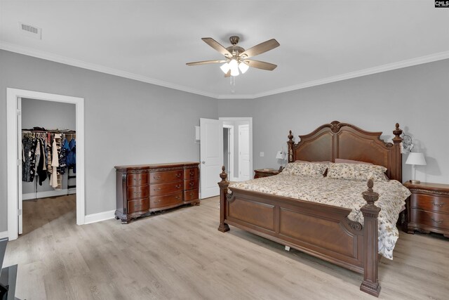 bedroom with light hardwood / wood-style flooring, ceiling fan, a walk in closet, ornamental molding, and a closet